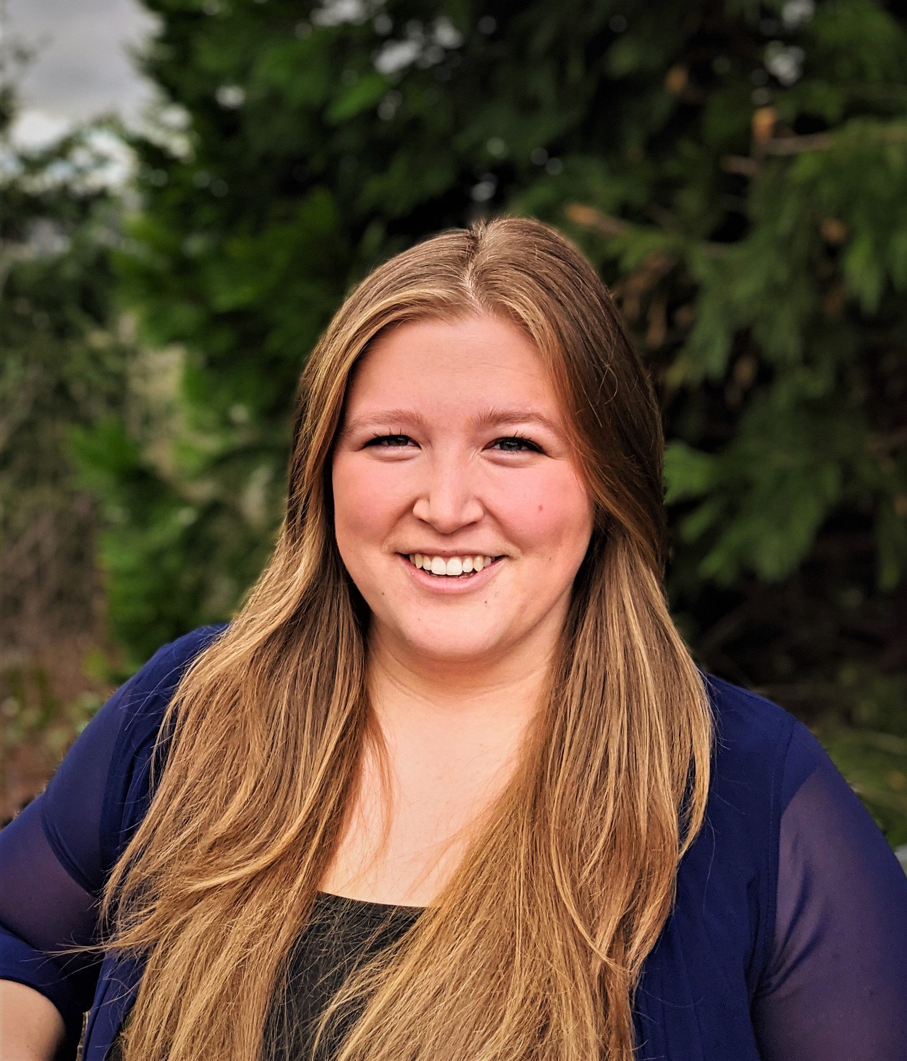 Headshot of woman smiling in front of trees