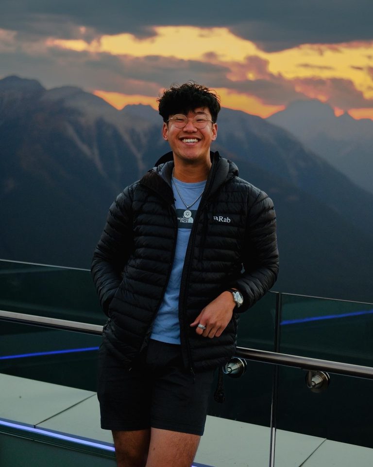 David Yun, Opportunity Scholar, standing in front of a sunset over a mountain range