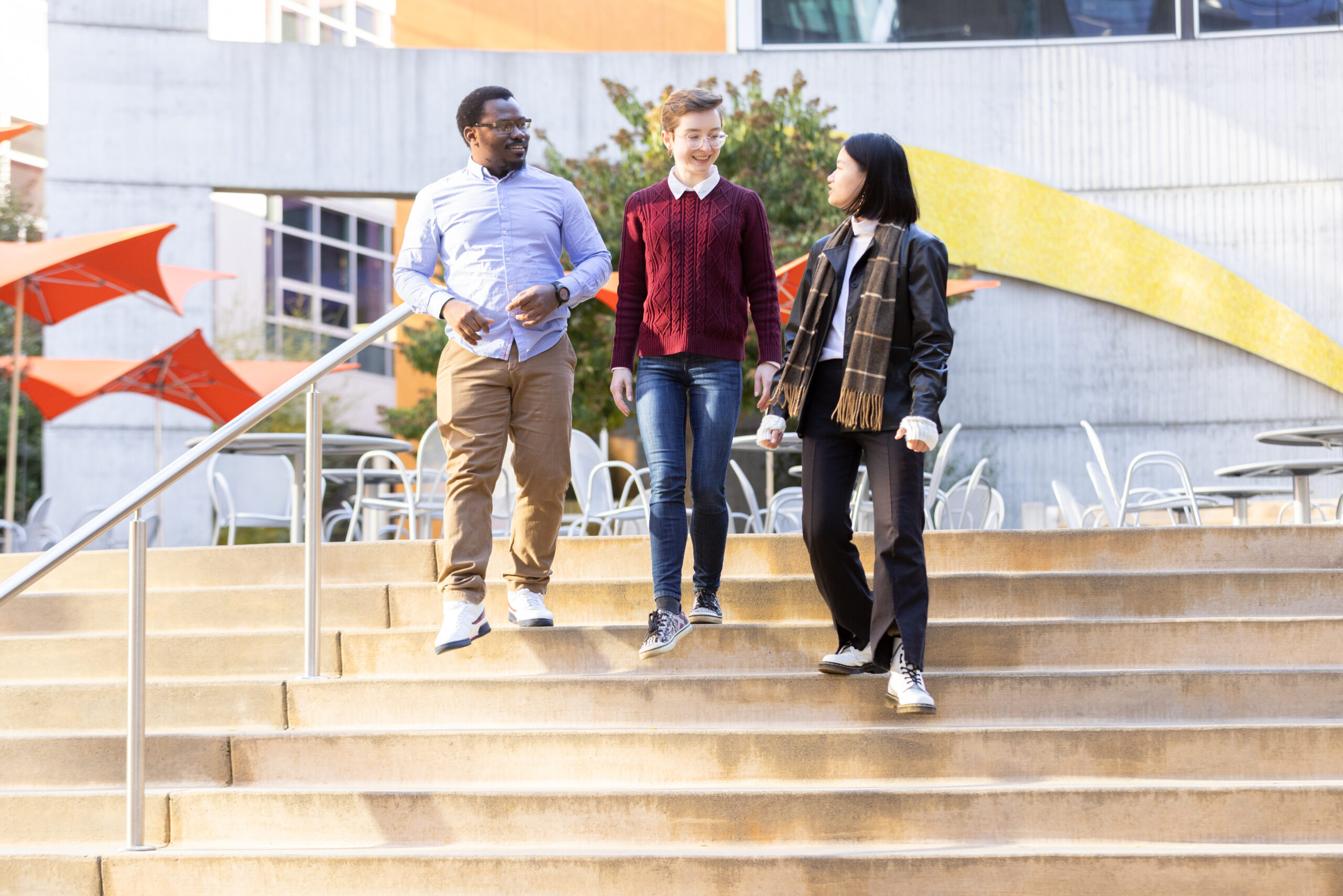 Three scholars walking downstairs outside, talking to each other