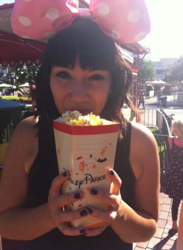 Jess at Disneyland eating popcorn with mouse ears on