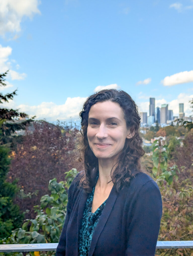 Woman smiling for a photo in front of greenery