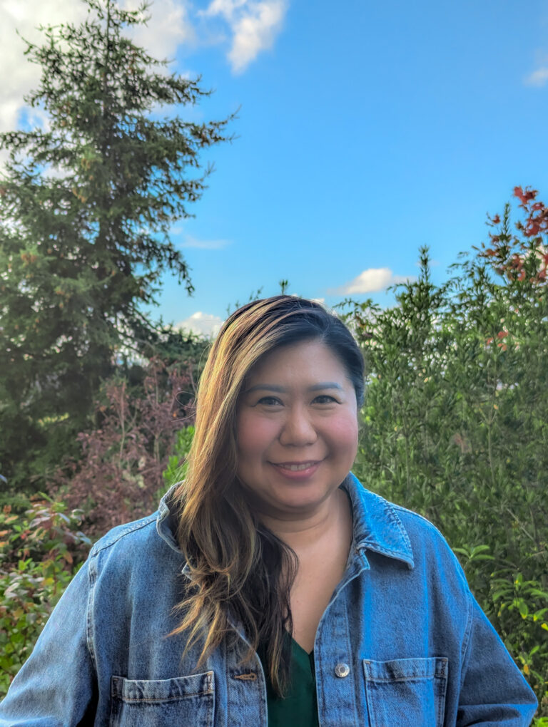 Woman smiling for a photo in front of greenery