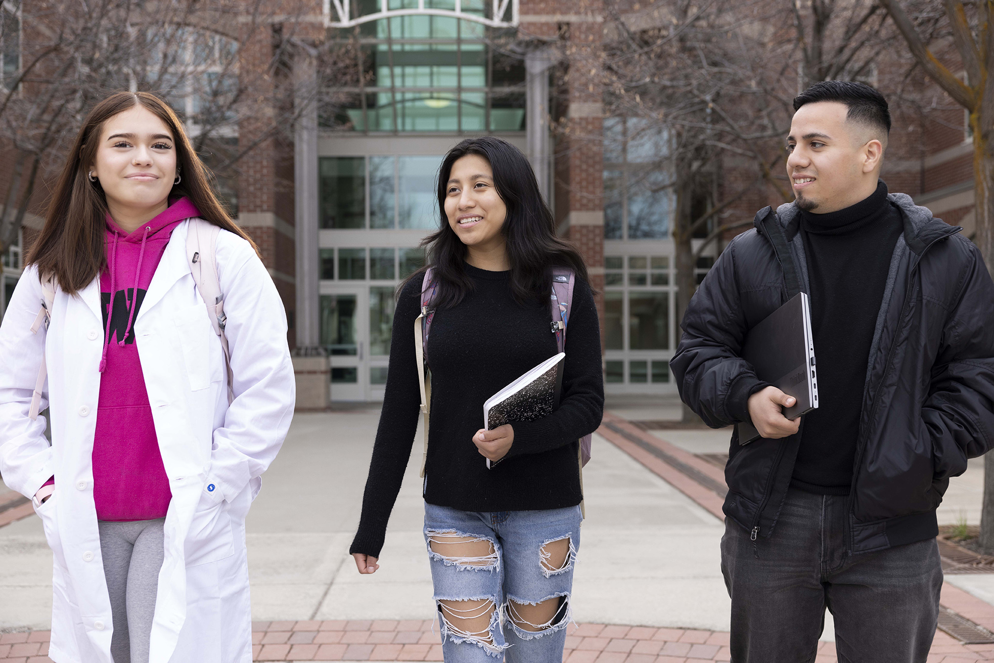 Three students walking on a campus.