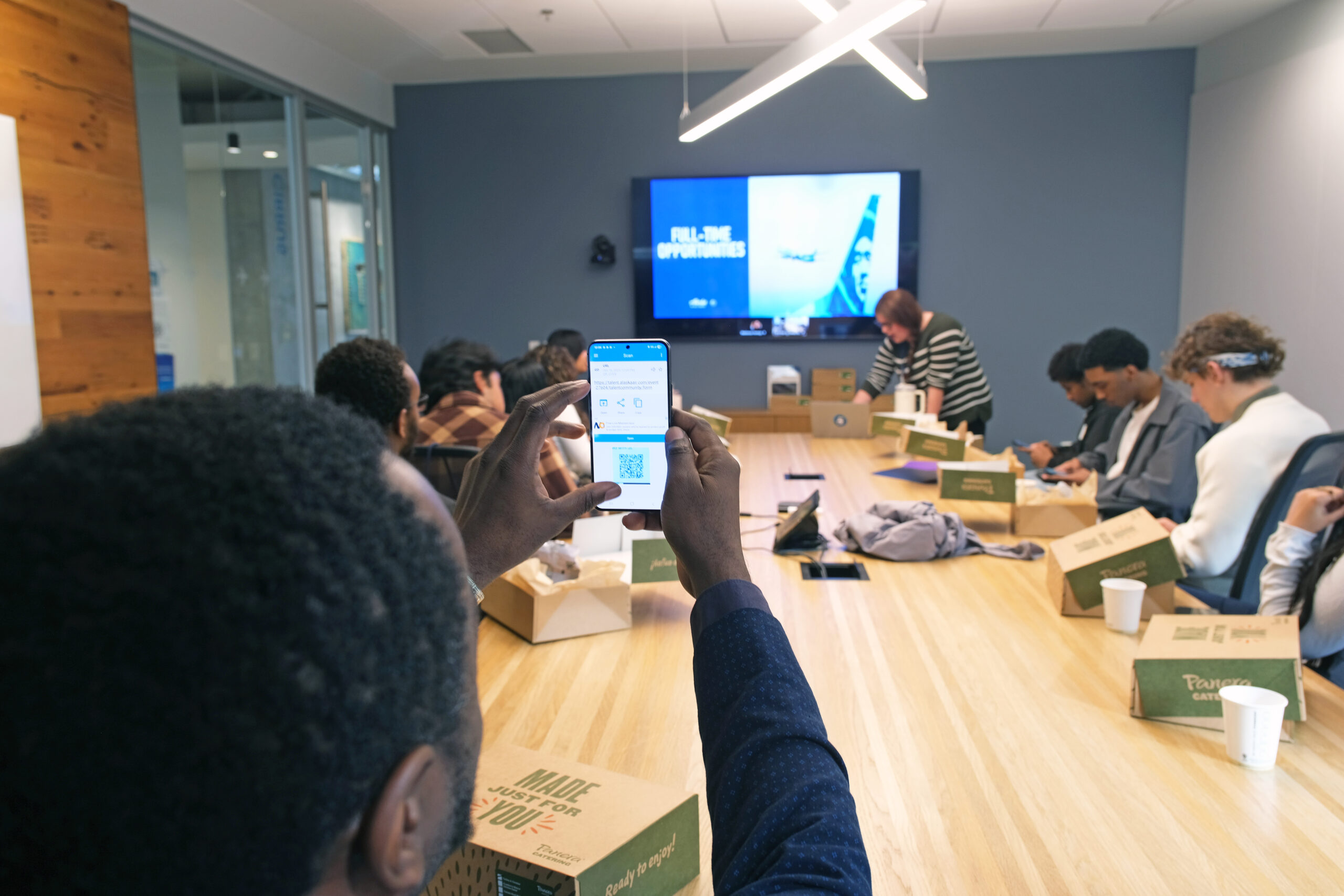 an Opportunity Scholar with his phone raised taking a photo of a screen 