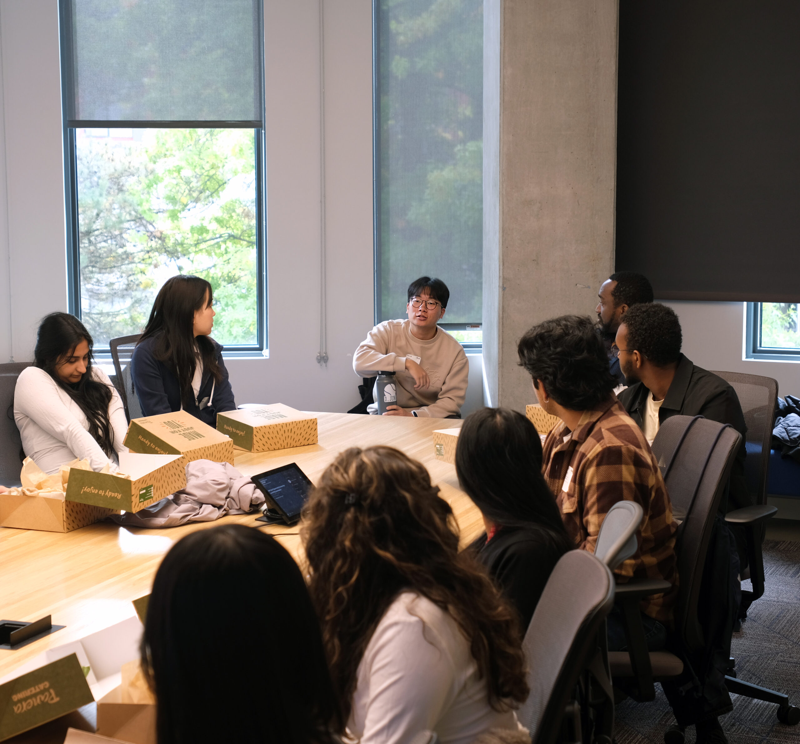 A group of Scholars turned looking at one asking a question in a conference room.